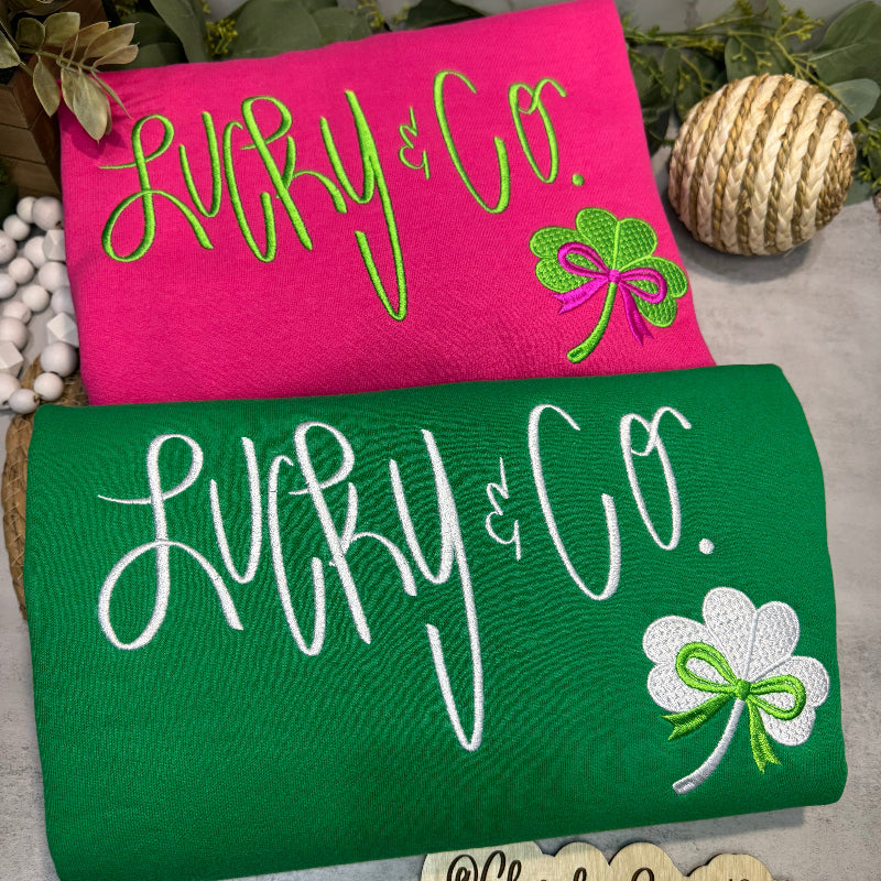Two sweatshirts, one pink and one green, with decorative elements.