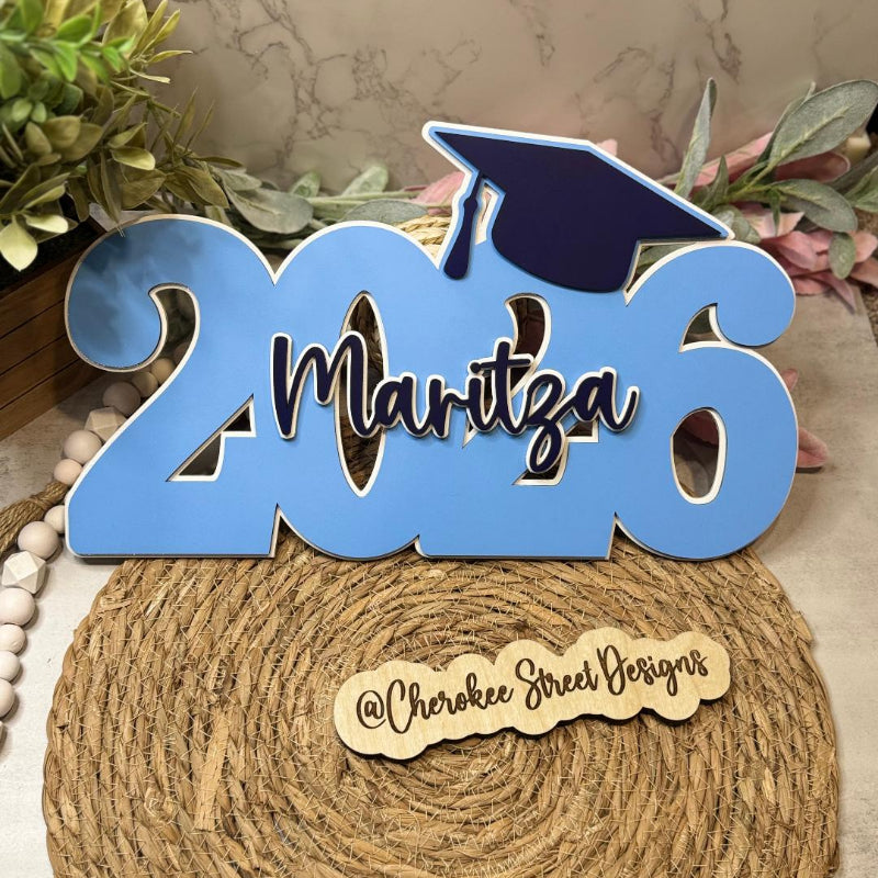 Graduation-themed decorative sign with '2026' and a cap