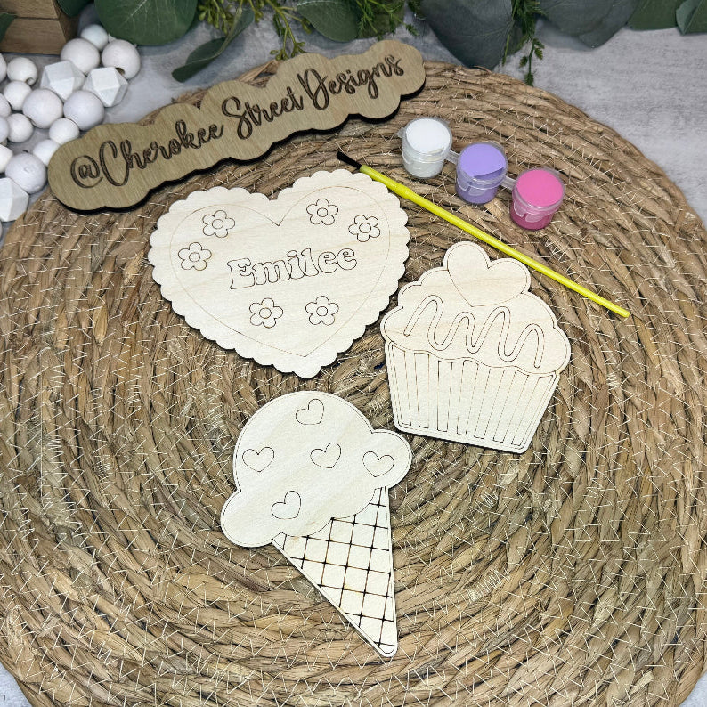 Decorative cutouts of a heart, cupcake, and ice cream cone with 'Emilie' 