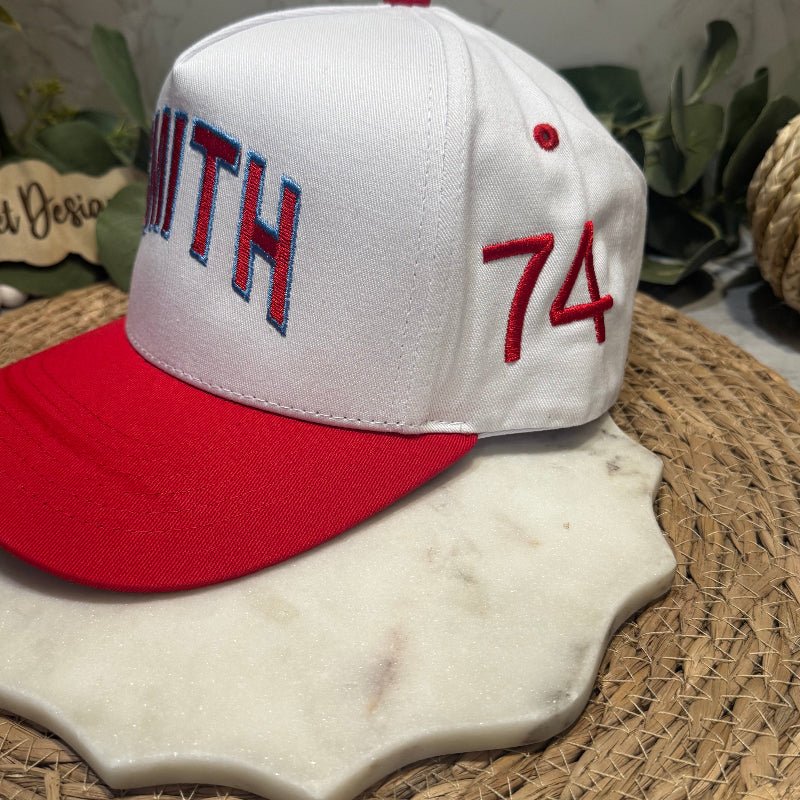 White and red cap with 'Smith 74' text on a marble surface with plants in the background