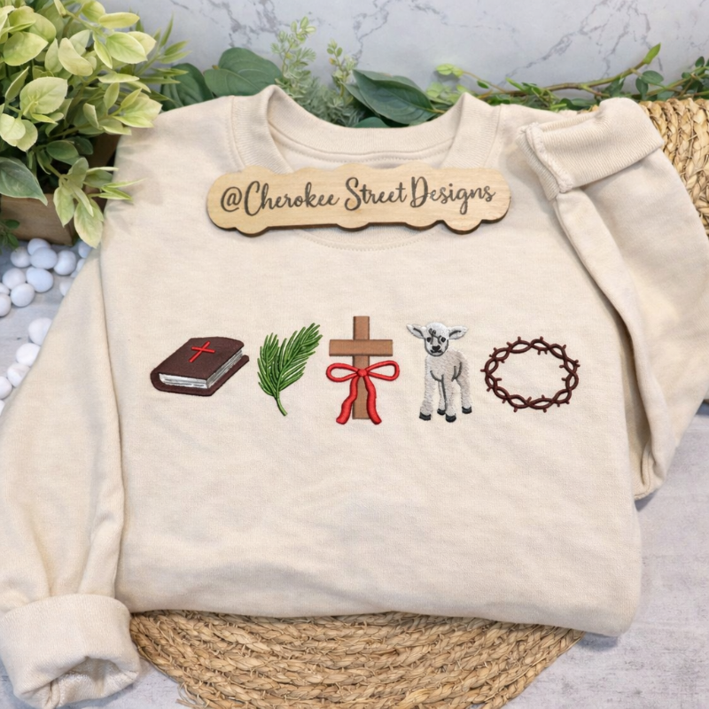 Beige sweatshirt with embroidered designs and 'Cherokee Street Designs' label on a neutral background.
