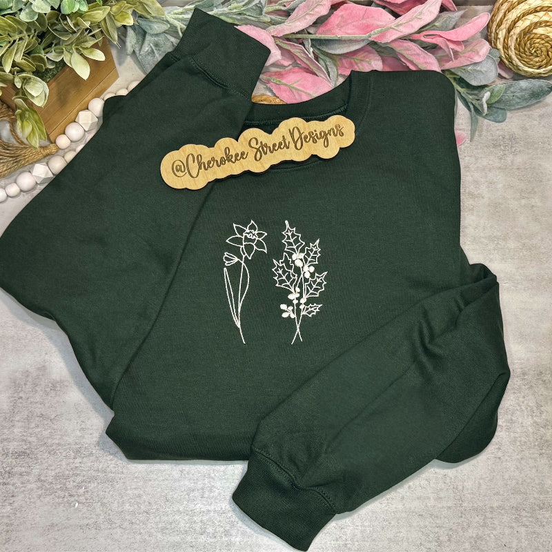 Green sweatshirt with floral designs on a decorative surface with 'Cherokee Street Designs' branding.
