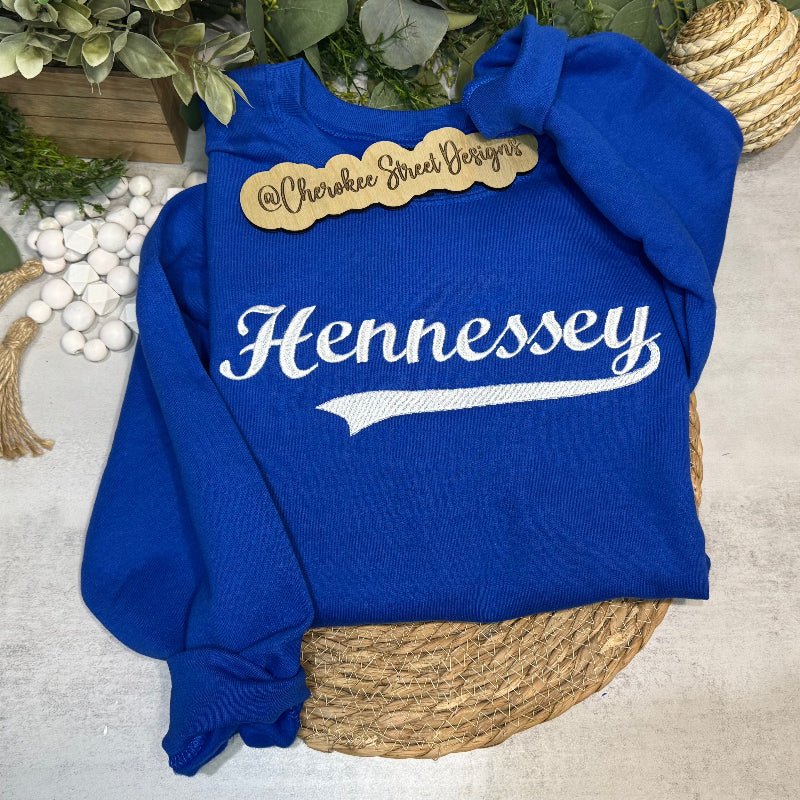 Blue sweatshirt with 'Hennessey' text on a textured surface with decorative elements.