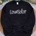 Black sweatshirt with 'Counselor' text on a textured surface with greenery