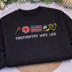 Black sweatshirt with embroidered graphics and 'Firefighter Wife Life' text on a textured surface.
