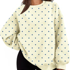A woman wearing an oversized cream-colored sweatshirt with a blue polka dot pattern, paired with black shorts.