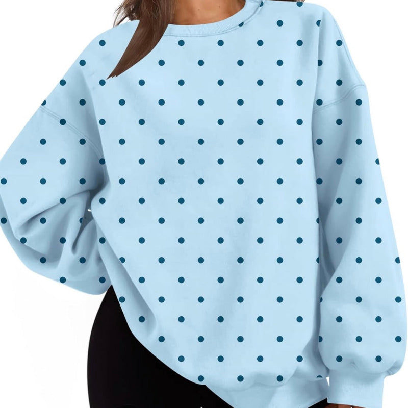 A woman wearing a light blue long-sleeve sweatshirt with a dark blue polka dot pattern, paired with black shorts, shown against a plain white background.