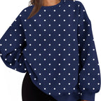 A woman wearing a navy blue crewneck sweatshirt with a white polka dot pattern, paired with black shorts, shown against a plain white background.