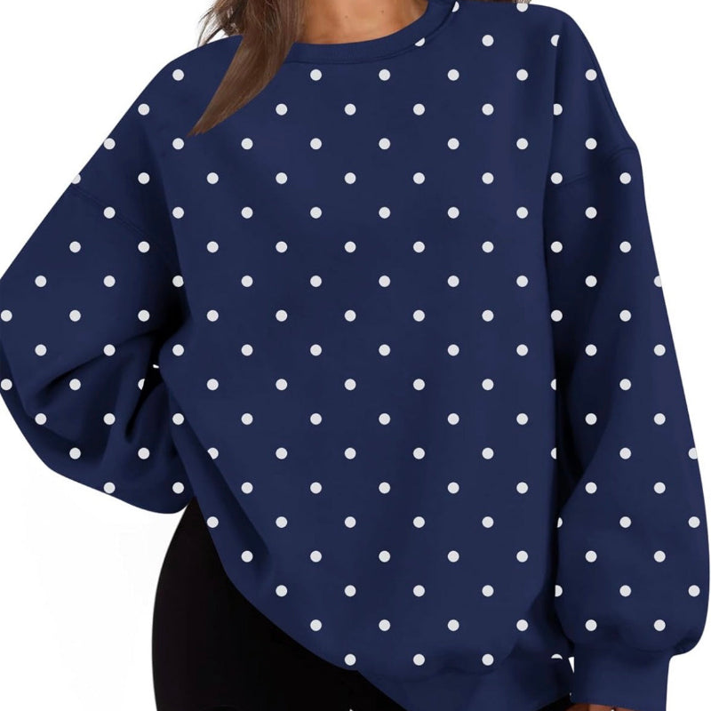 A woman wearing a navy blue crewneck sweatshirt with a white polka dot pattern, paired with black shorts, shown against a plain white background.