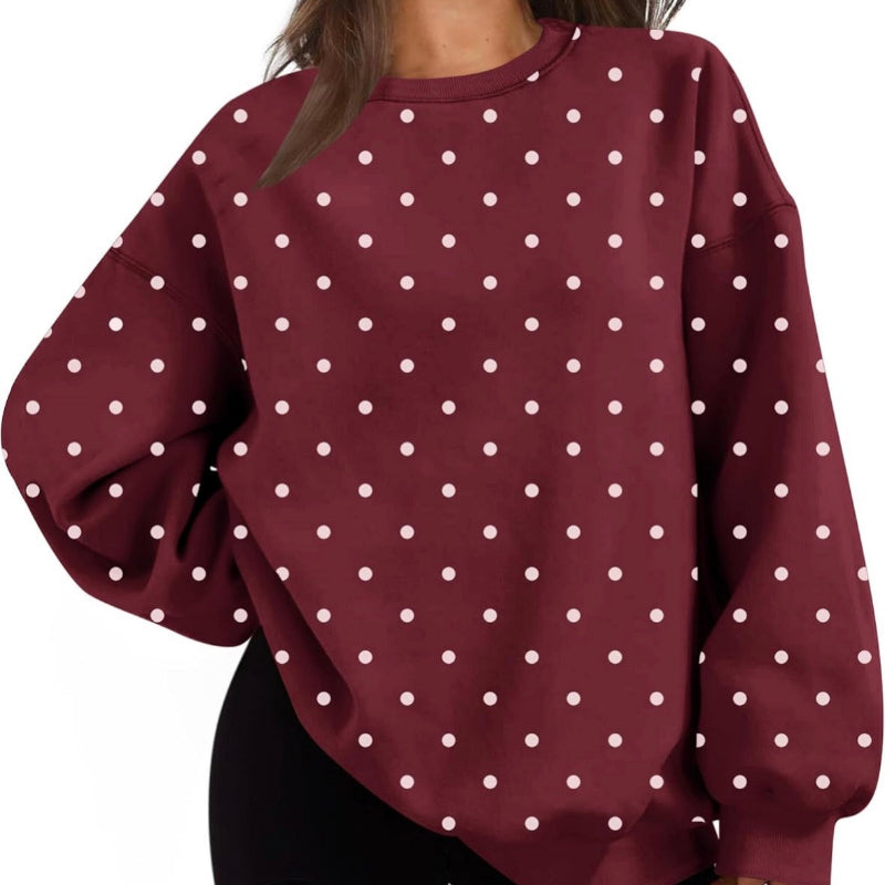 A woman wearing an oversized crewneck sweatshirt in burgundy with a white polka dot pattern, paired with black leggings, shown against a plain white background.