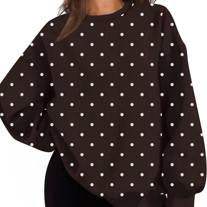 A woman wearing an oversized dark brown long-sleeve top with a white polka dot pattern, paired with black shorts, shown against a plain white background.