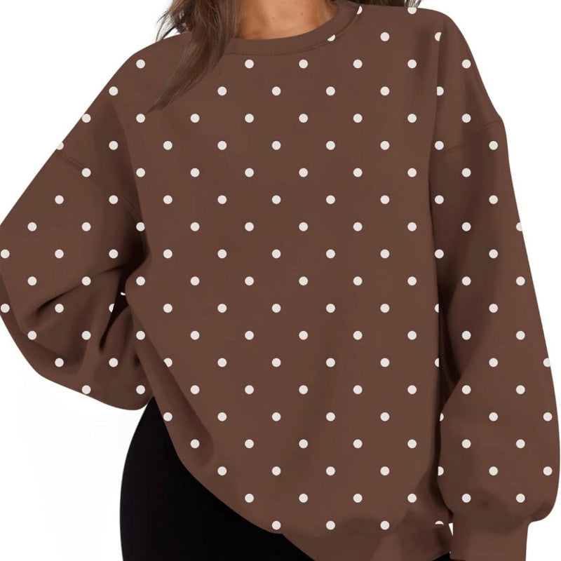 A woman wearing an oversized brown sweatshirt with a white polka dot pattern, paired with black shorts, shown against a plain white background.