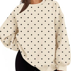 A woman wearing a cream-colored oversized sweatshirt with a black polka dot pattern, paired with black shorts, shown against a plain white background.