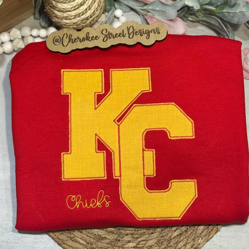 Red sweatshirt with yellow 'KC' logo 