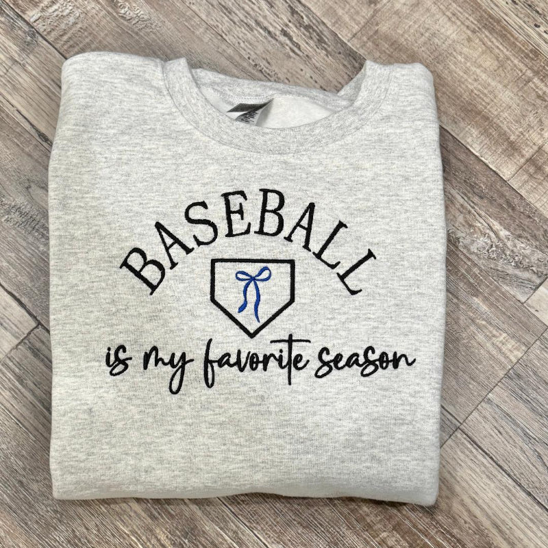Folded gray sweatshirt with 'Baseball is my favorite season' text 