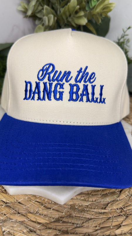A two-tone baseball cap with an off-white crown and a royal blue brim. The front of the cap features blue embroidered text reading 'Run the DANG BALL'.